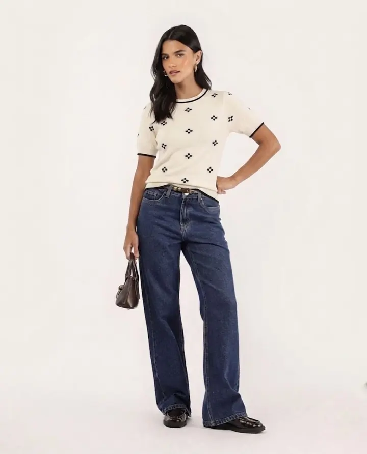 Blusa de tricô creme de manga curta com mini floral marinho e vivo preto na gola, com calça jeans.